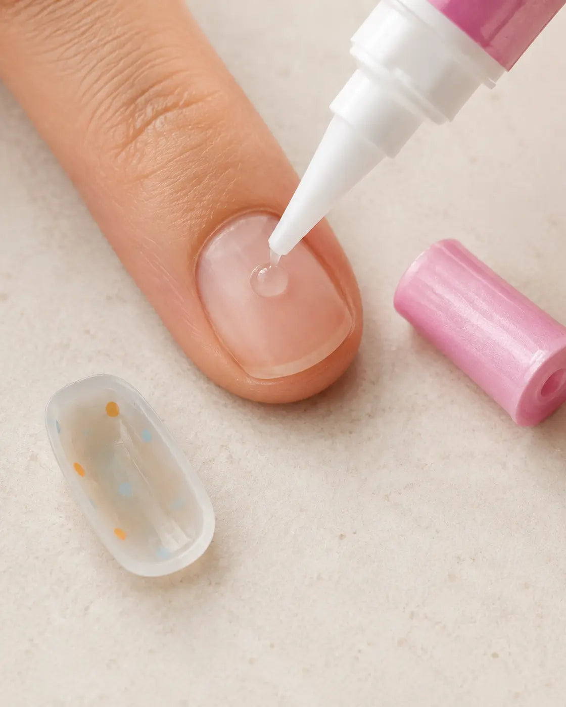 Nail glue being applied carefully away from the cuticle and surrounding skin