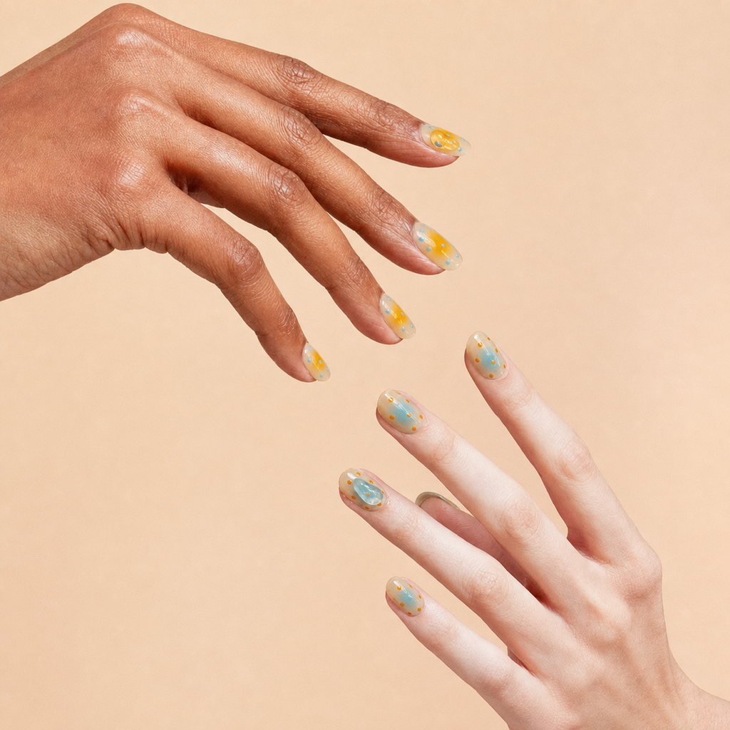 Two hands wearing Breathe nude aura press-on nails with orange and blue details on a peach background

