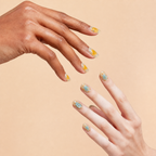 Two hands wearing Breathe nude aura press-on nails with orange and blue details on a peach background
