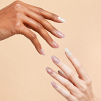 Two hands wearing Deep Within pink iridescent crystal press-on nails on a peach background