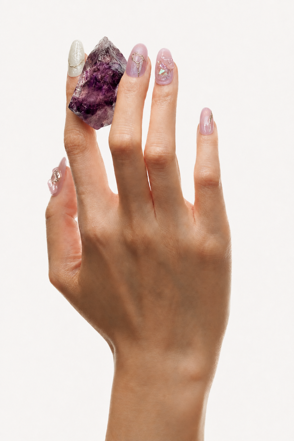 Hand wearing Deep Within pink iridescent press-on nails with gold lines and crystal shards
