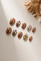 Flat lay of Golden Hour brown metallic press-on nails with silver foil and citrine accents
