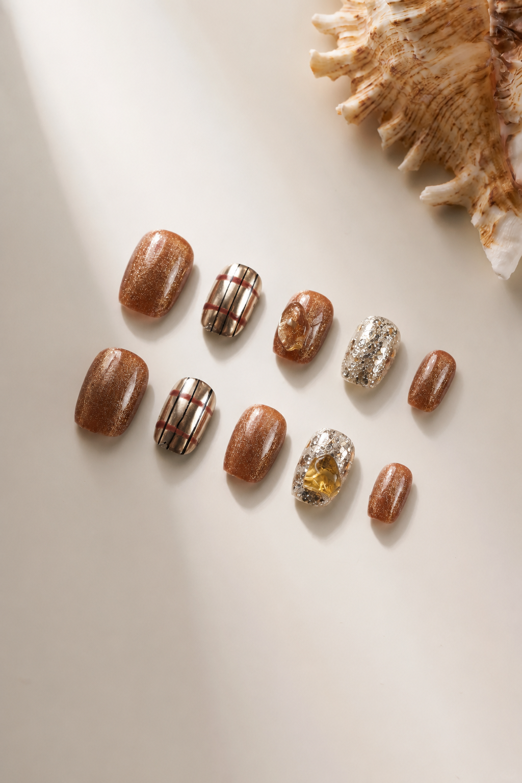 Flat lay of Golden Hour brown metallic press-on nails with silver foil and citrine accents
