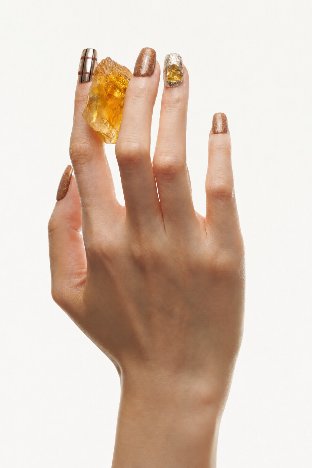 Hand wearing Golden Hour brown metallic press-on nails with silver foil and citrine accents
