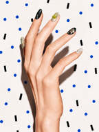 Editorial hand wearing Green Calm green aventurine press-on nails on a blue dot patterned background