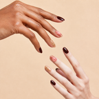 Two hands wearing In Bloom burgundy floral rose quartz press-on nails on a peach background