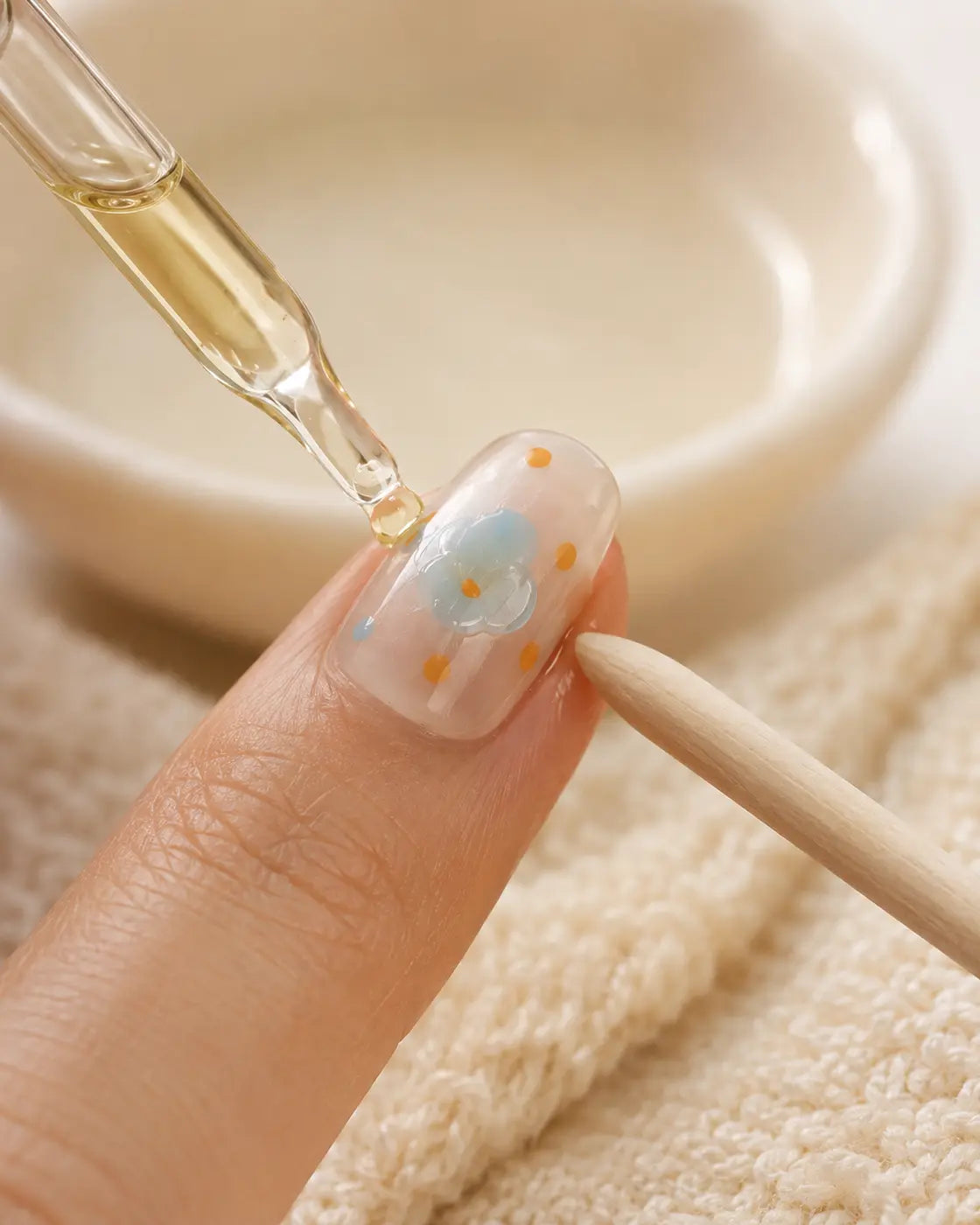 Oil being worked carefully around the edges of a loosening press-on nail