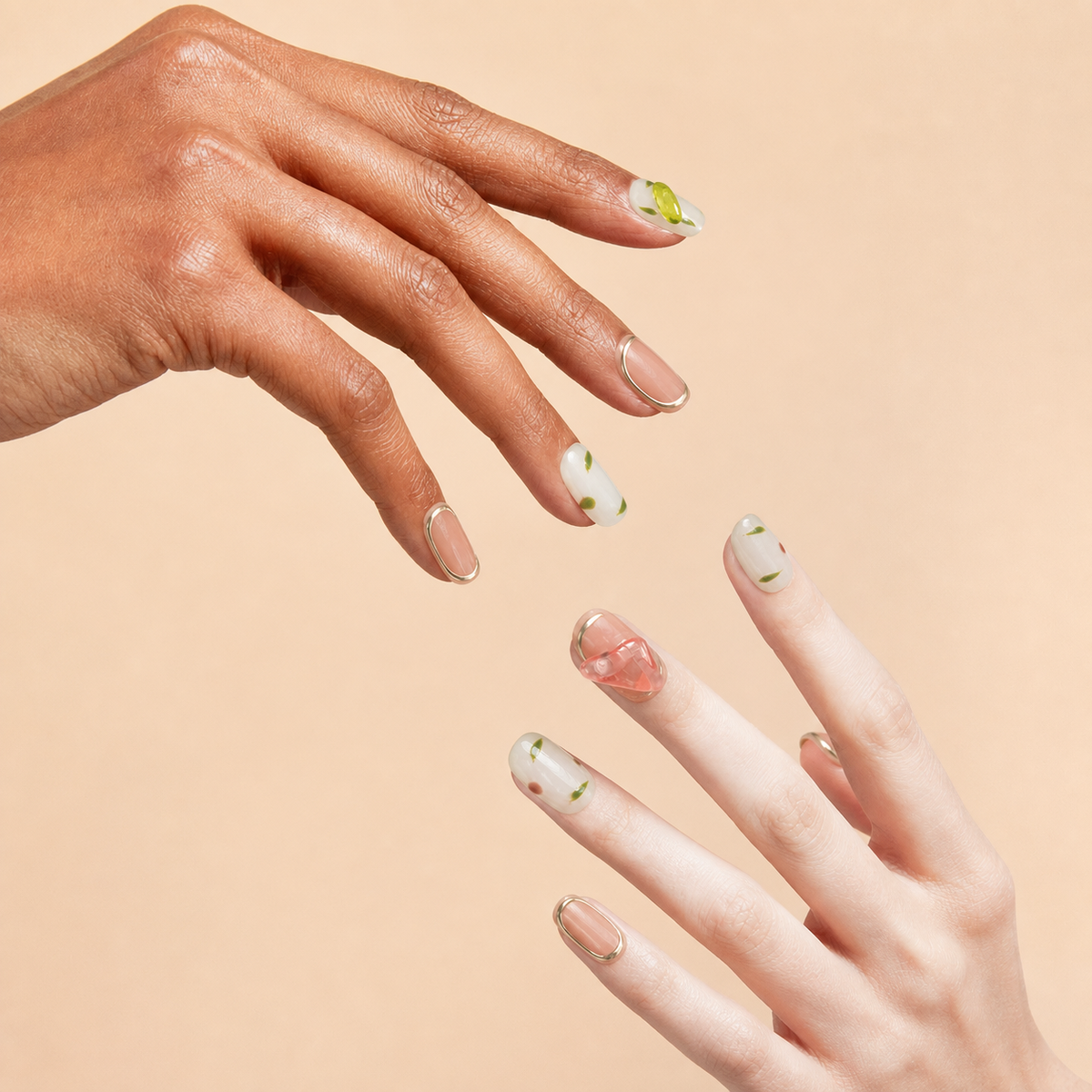 Two hands wearing New Sprout pink green floral press-on nails on a peach background