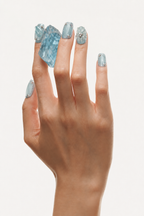 Hand wearing Open Sky blue 3D floral press-on nails with white flowers, rhinestones and aquamarine
