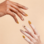 Two hands wearing Quiet Light amber floral crystal press-on nails on a peach background