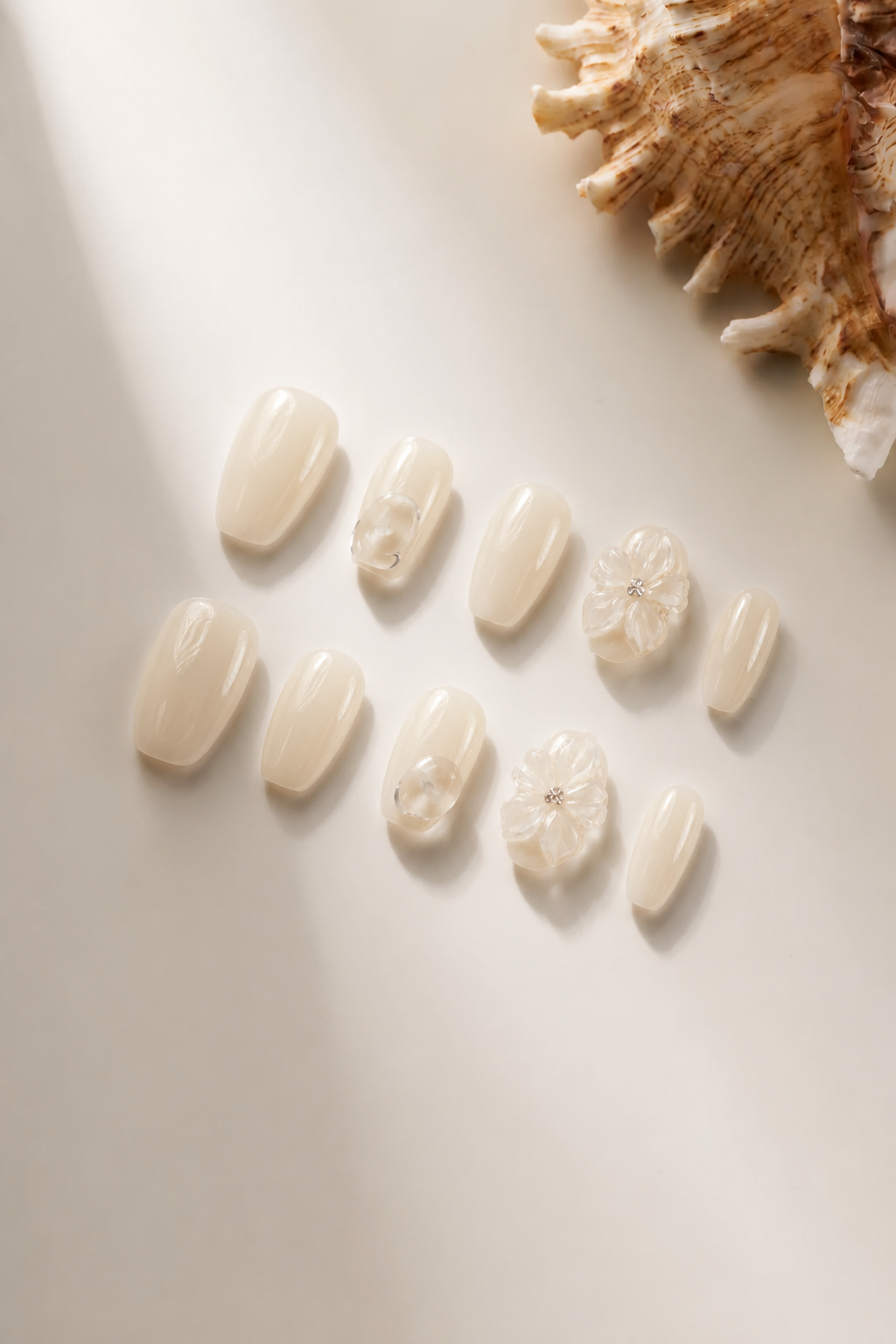 Flat lay of Untangled white 3D floral press-on nails with clear quartz accents
